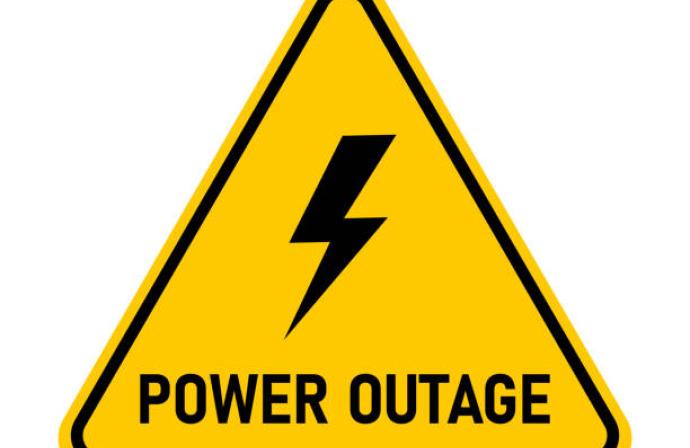 Yellow triangle sign with lightning bolt in the middle and the words power outage