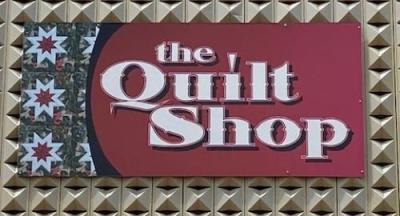 The quilt shop signage on maroon background